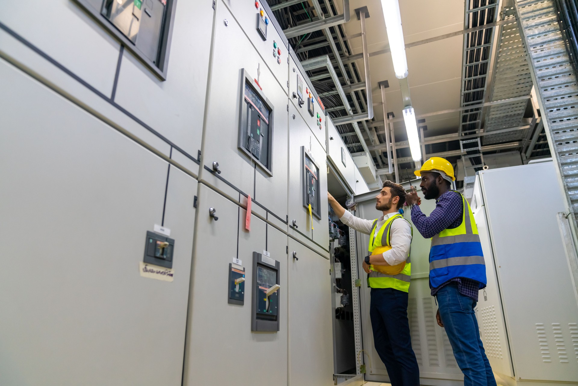 Male engineer teamwork working at factory server electric control panel room.